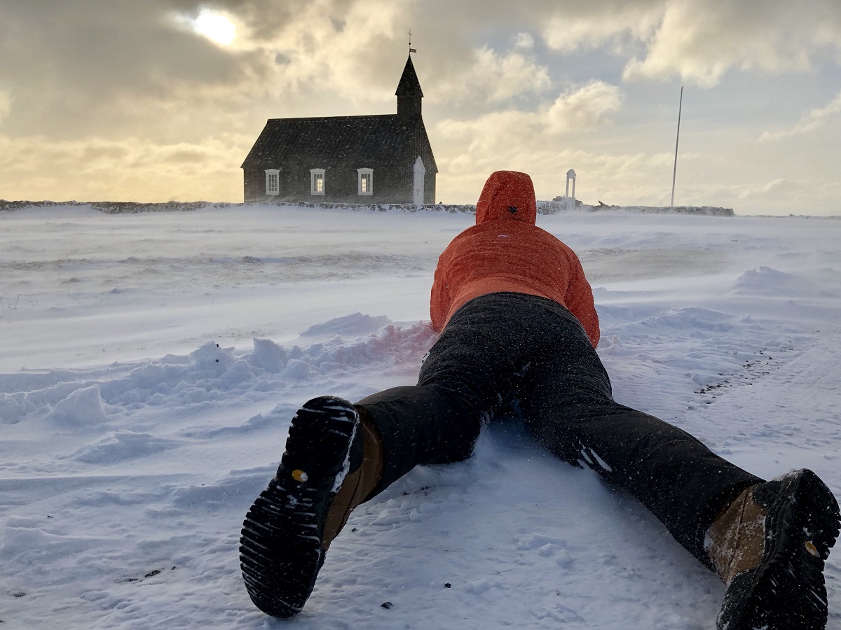 Liggend in de sneeuw fotografeert deze reiziger het mooie kerkje bij Budir op Snaefellsness, IJsland.