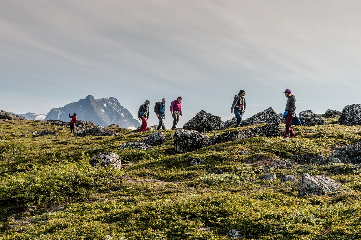 Een groep reizigers wandelt tussen rotsblokken in de Tasermiut fjord in zuid Groenland.