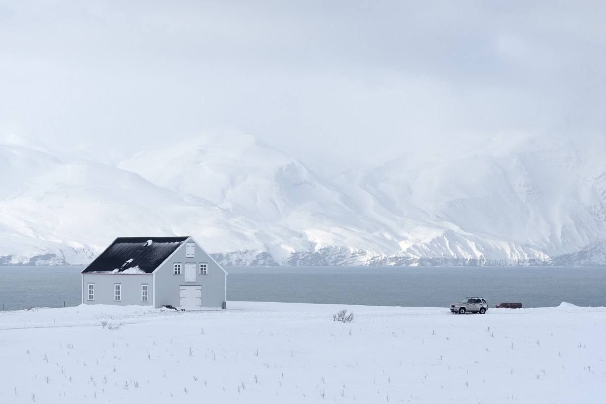 Een licht blauw huis aan de fjord in een besneeuwd landschap in Noord IJsland.