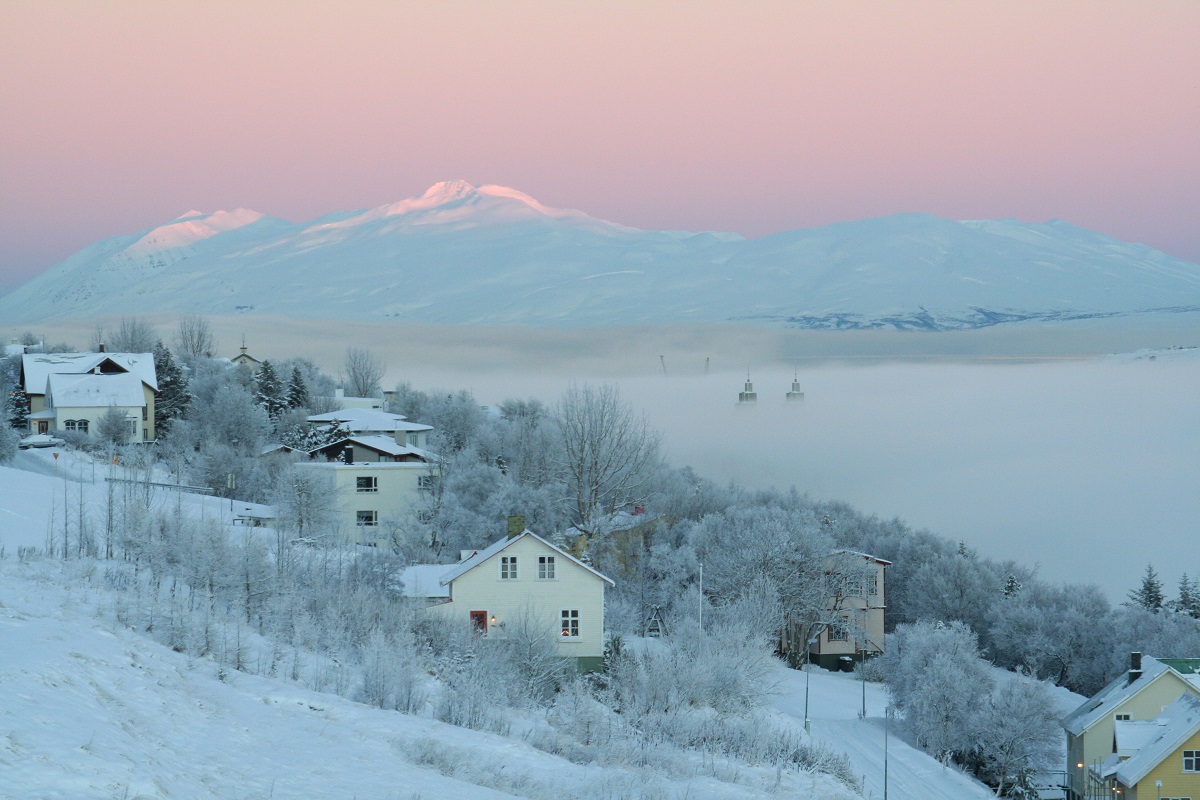Huizen op de heuvel met op de achtergrond de paarse lucht van zonsondergang, in Akureyri Noord IJsland.