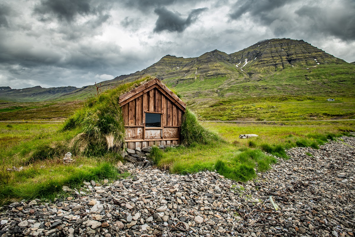 Een turfhuisje in het oosten van IJsland midden in een groen landschap.