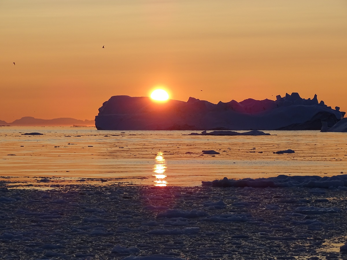 Zonsondergang met uitzicht op een ijsberg in Ilulissat, west Groenland.