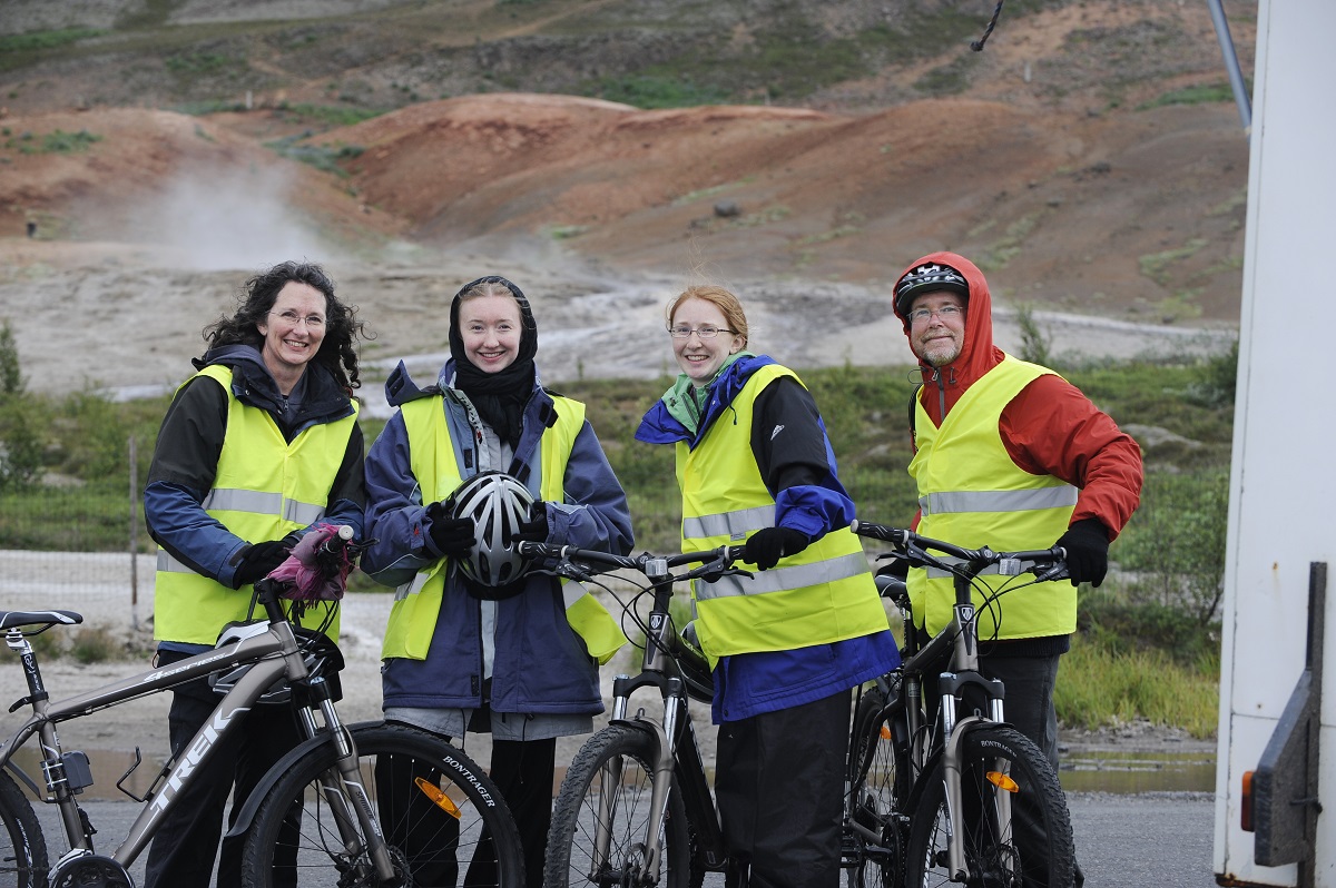 Groepje sportieve fietsers in gele hesjes maken een foto bij de stoombron in zuid IJsland.