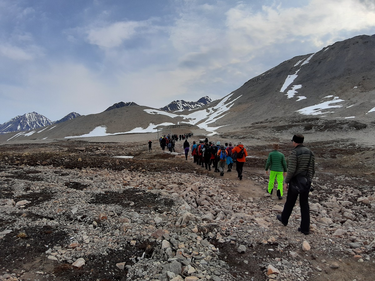 Een groep wandelaars die aan het wandelen zijn in de bergen, met besneeuwde toppen, op Spitsbergen.