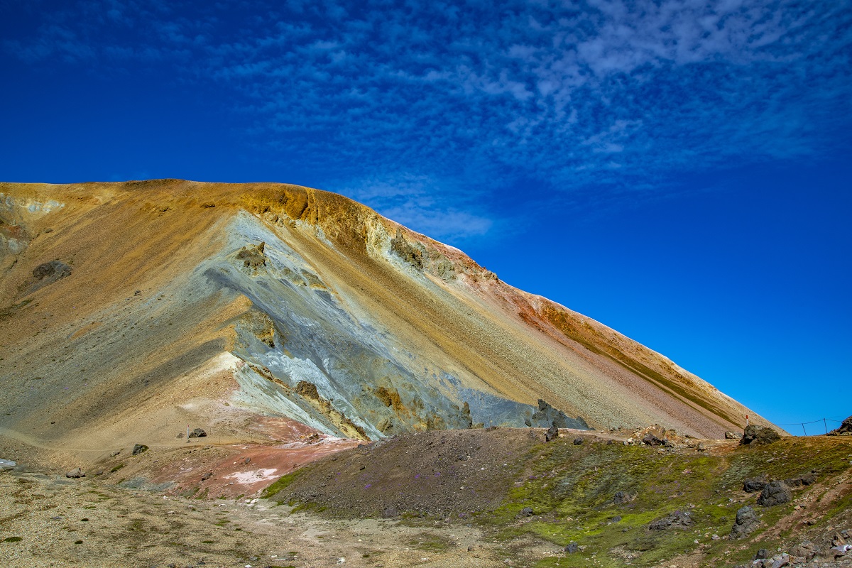 Een kleurrijke heuvel in Landmannalauger, in de hooglanden van IJsland, met strak blauwe lucht op de achtergrond.