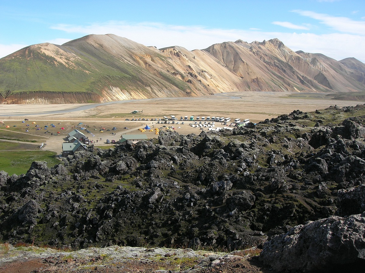 Landschap met lavaveld, centrale hut en kleurrijke bergen in de hooglanden bij Landmannalaugar, IJsland.