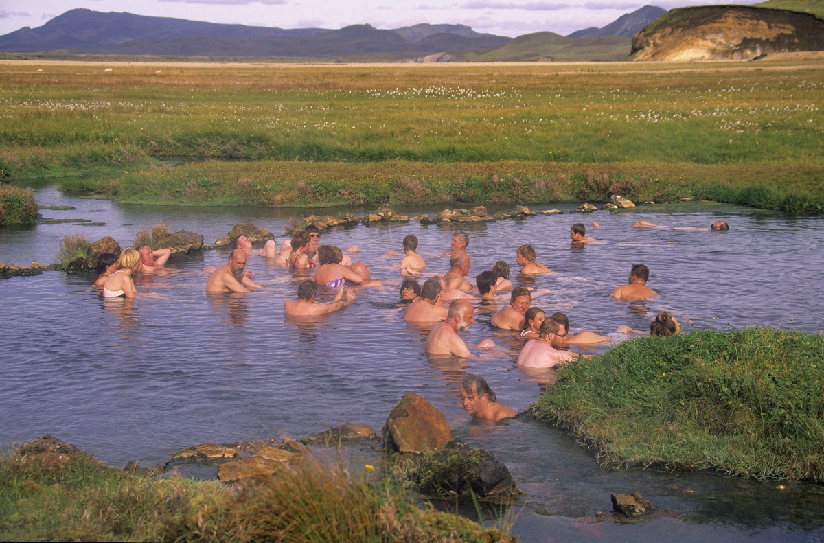 Mensen badderen in de warme rivier in een groen landschap in de Landmannalaugar, in de hooglanden in IJsland.