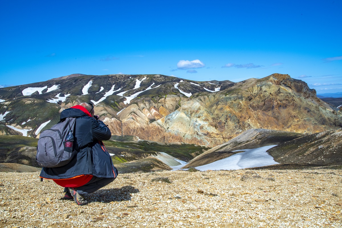 Reiziger is de kleurrijke bergen van de Landmannalauger, IJsland, met helder blauwe lucht aan het fotograferen.