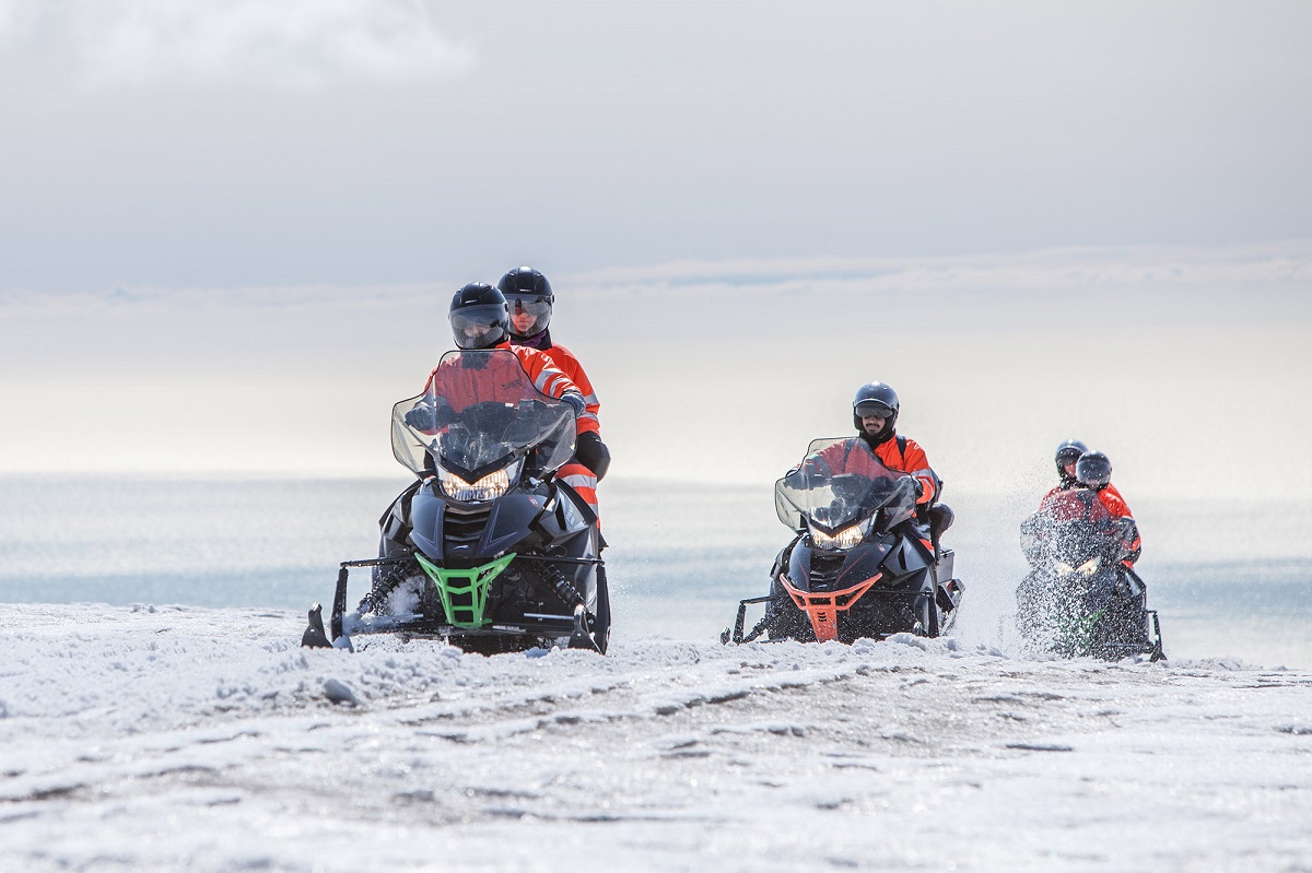 Een groepje sneeuwscooters rijdt door de sneeuw over de Solheimajokull in zuidwest IJsland.