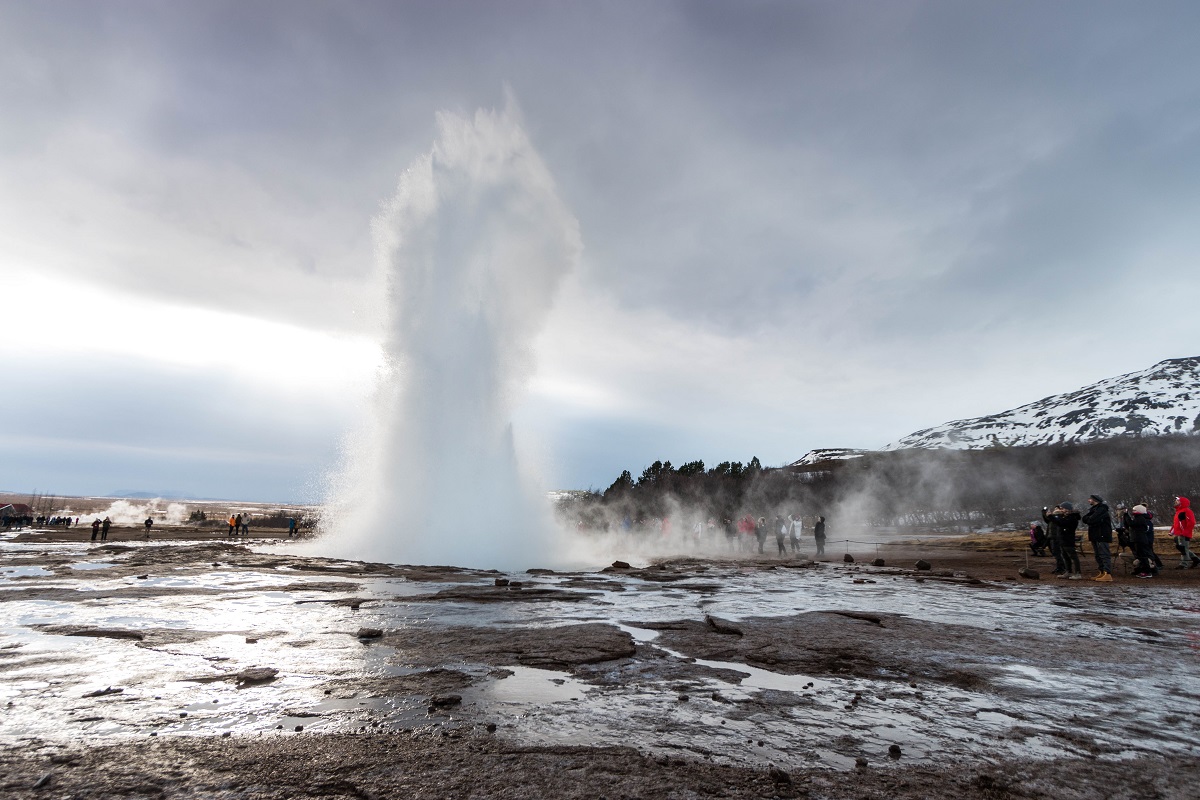 Reizigers worden nat van het stuifwater van de geiser Strokkur in het Golde Circle gebied in IJsland.