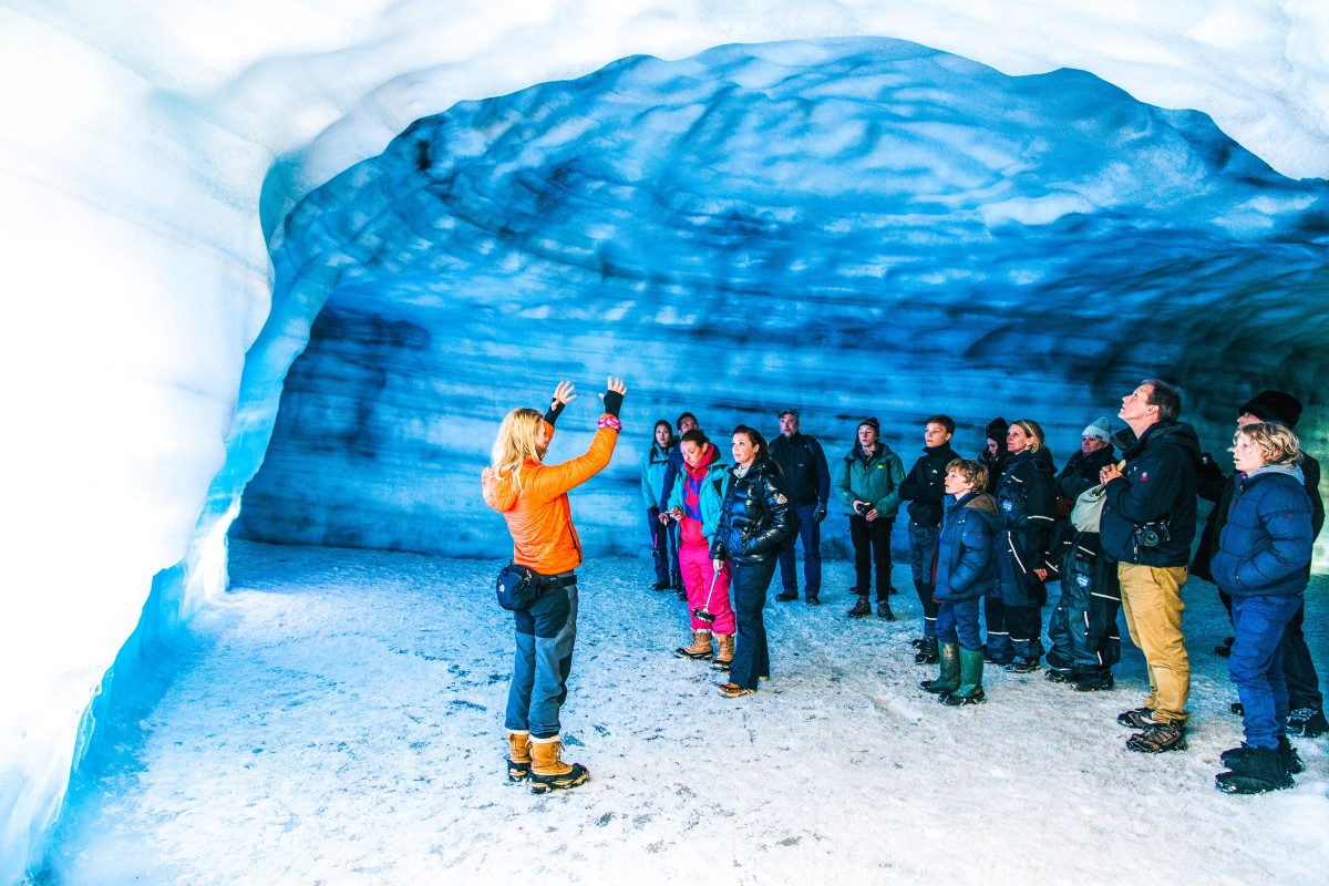 Een groep toeristen staat in de ijsgrot van Into The Glacier.