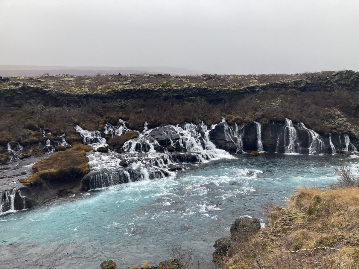 Onderaardse stromen van de Hraunfossar persen zich via de lavawand naar buiten.