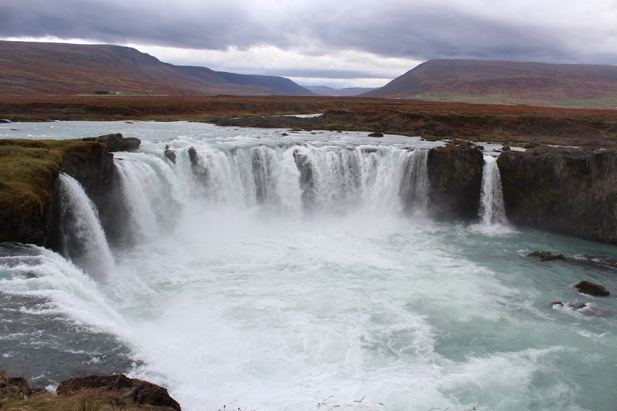 Herfstige kleuren bij de Godafoss, met bergen op de achtergrond.