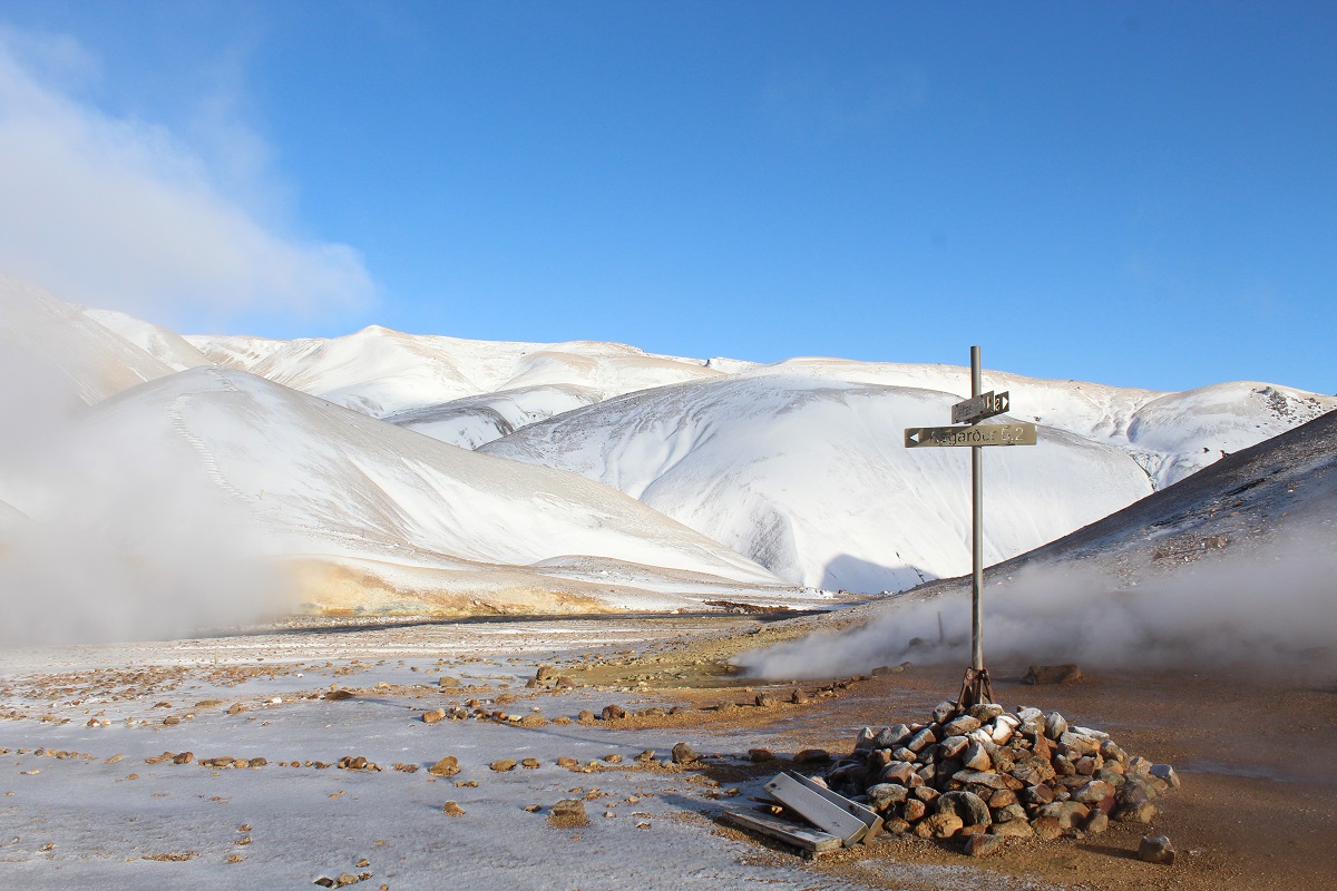 Een wegwijzer, met mist en sneeuw op de achtergrond, staat in een stenenhoop in Keringarfjöll.