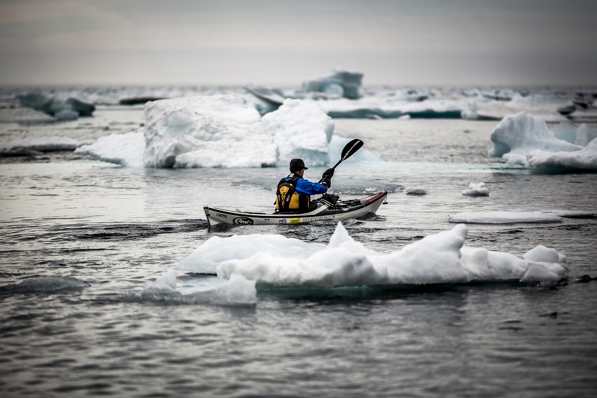 Kayakker drijft tussen de  ijsrotsen door vlakbij het dorpje Tasiilaq.