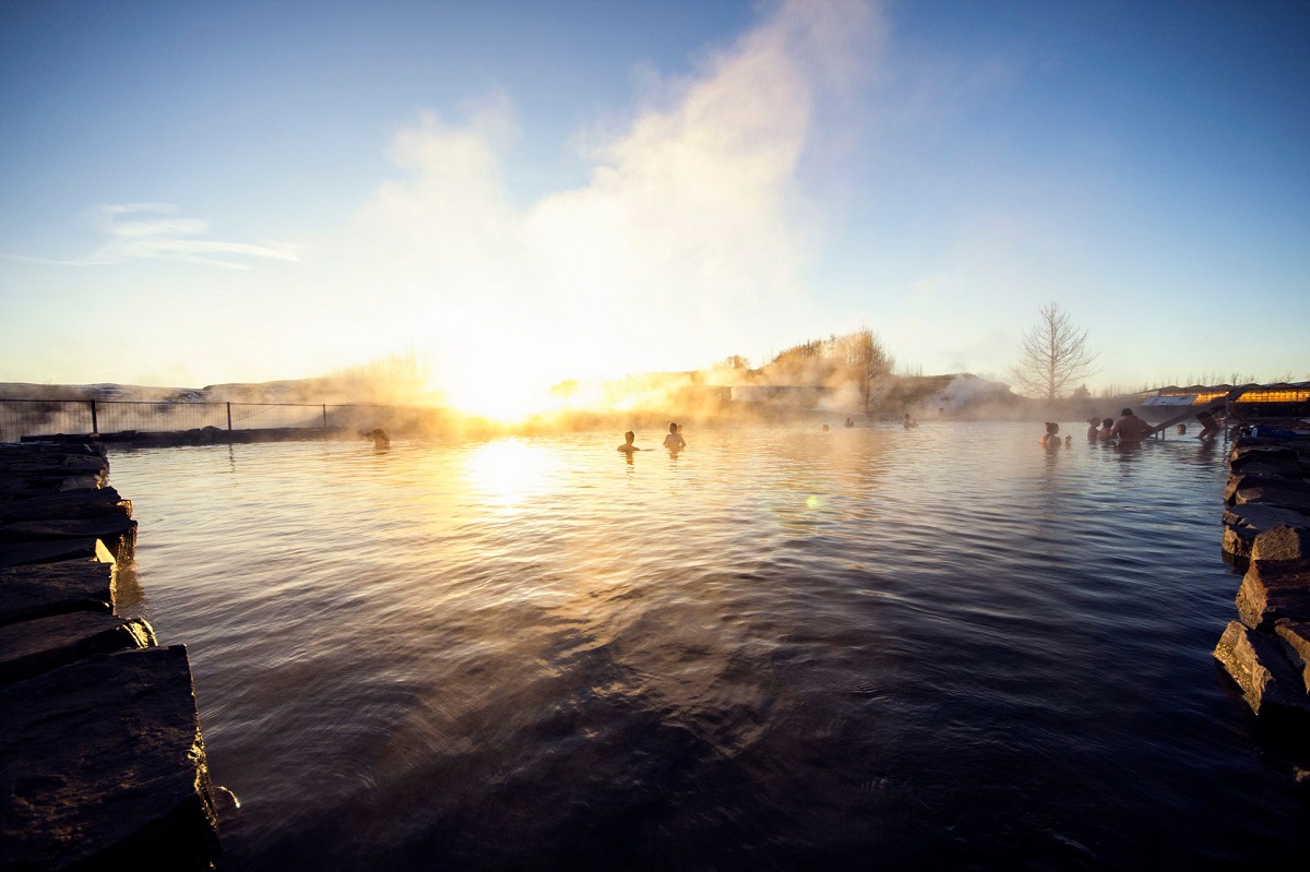 Reizigers in het stomende water van de Secret Lagoon in IJsland.