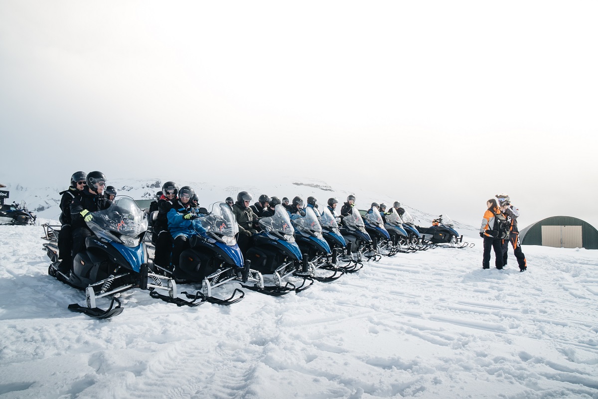 Sneeuscooters naast elkaar voor een sneeuwscootertour.