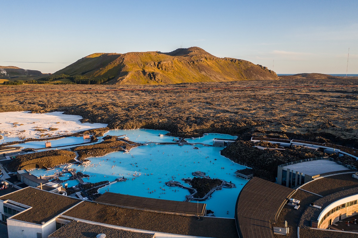 Een panorama uitzicht van bovenaf op de Blue Lagoon, met op de achtergrond sneeuw, bergen en de zonsopkomst.