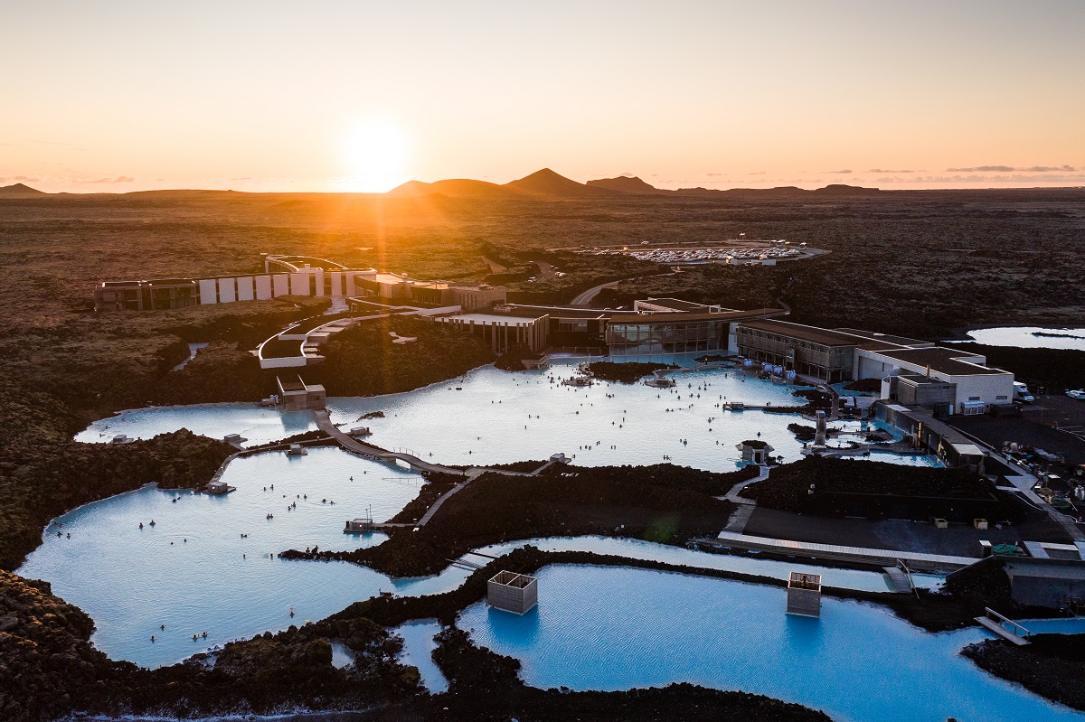 Een panorama uitzicht van bovenaf op de Blue Lagoon, een warmwaterbron in Reykjanes IJsland. Met zwemmende mensen en op de achtergrond bergen en de zonsondergang.