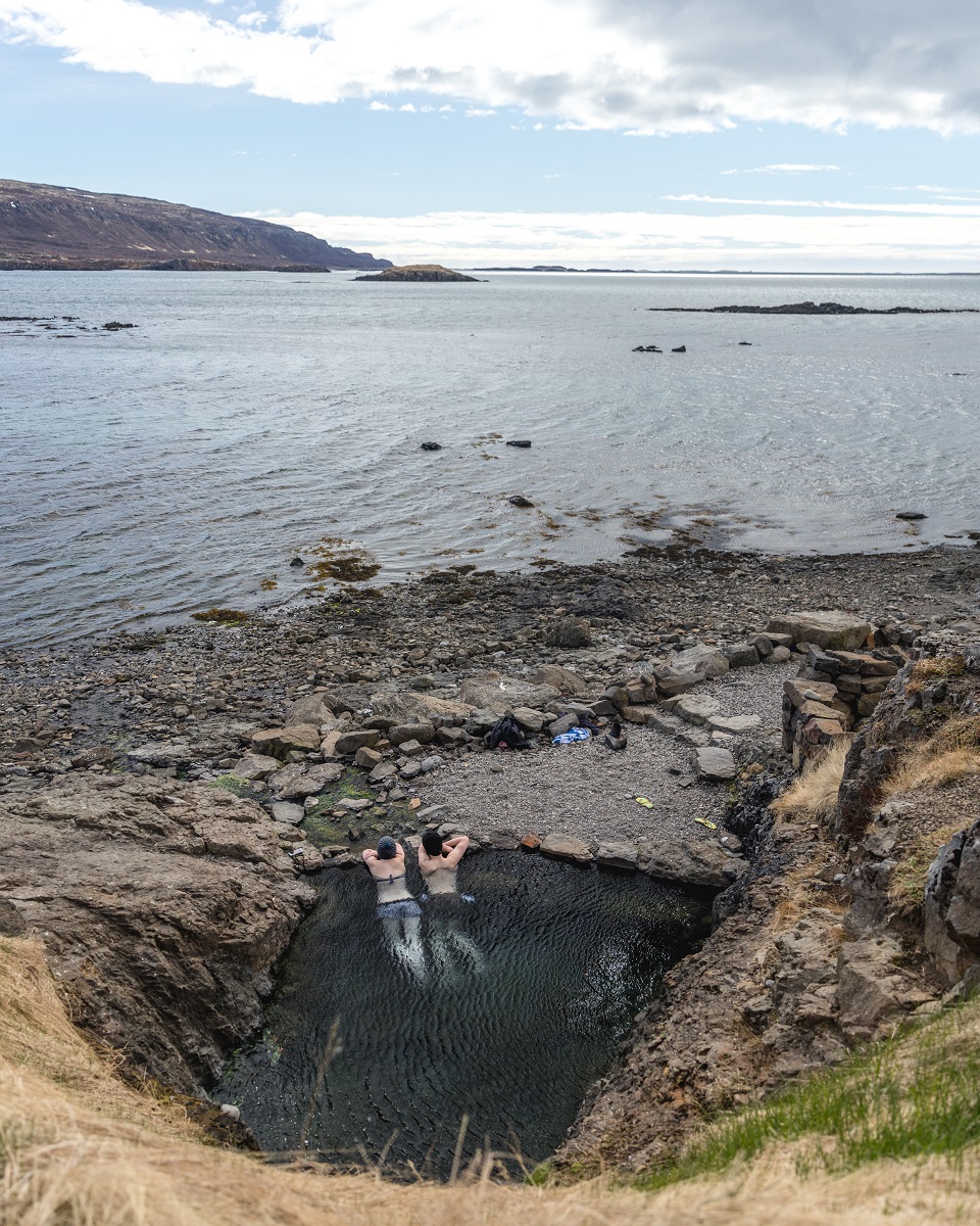 Een koppel baddert in de geothermische warmwaterbron Hellulaug in de Westfjorden in IJsland. 