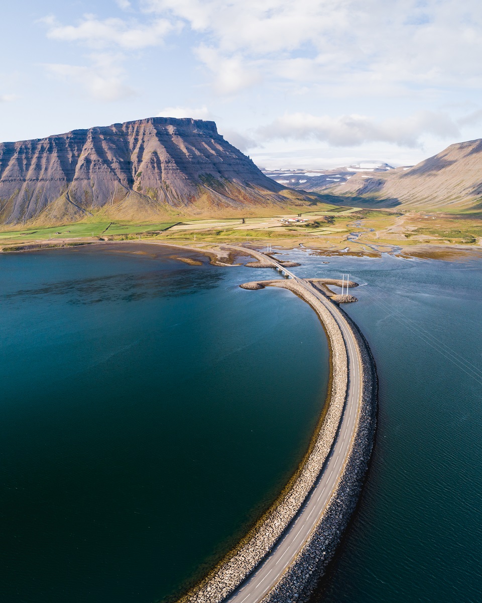 Een weg loopt over het water heen naar de andere kant van de Westfjorden in het plaatsje Pingeyri in IJsland.
