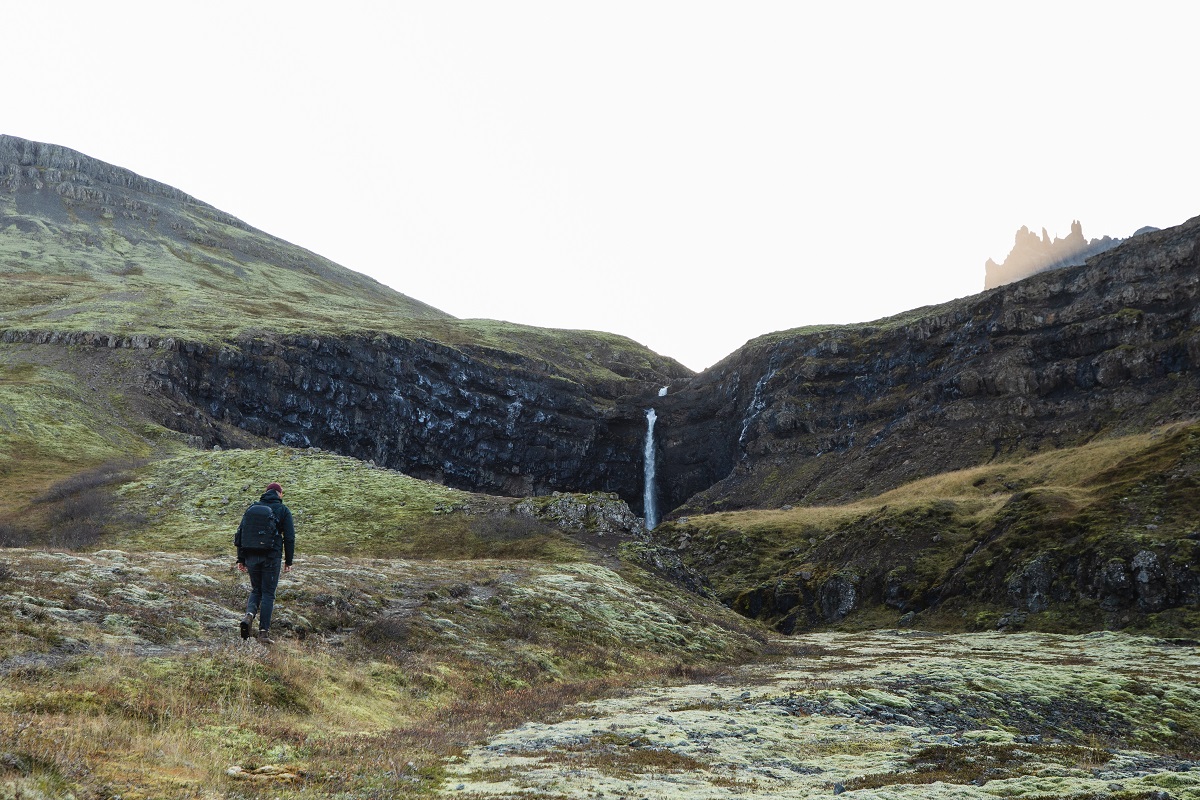 Een wandelaar loopt richting de Flögufoss waterval bij Breidalur in Oost IJsland. 