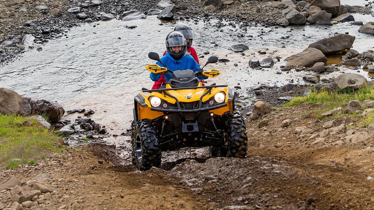 Met quad een heuvel op door een plas.