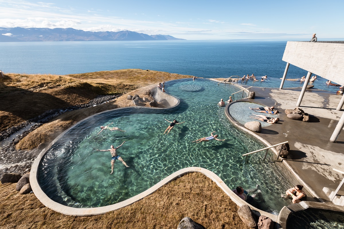 Reizigersrelaxen in het geothermisch warme water van Geosea met uitzicht over de baai van Husavik.