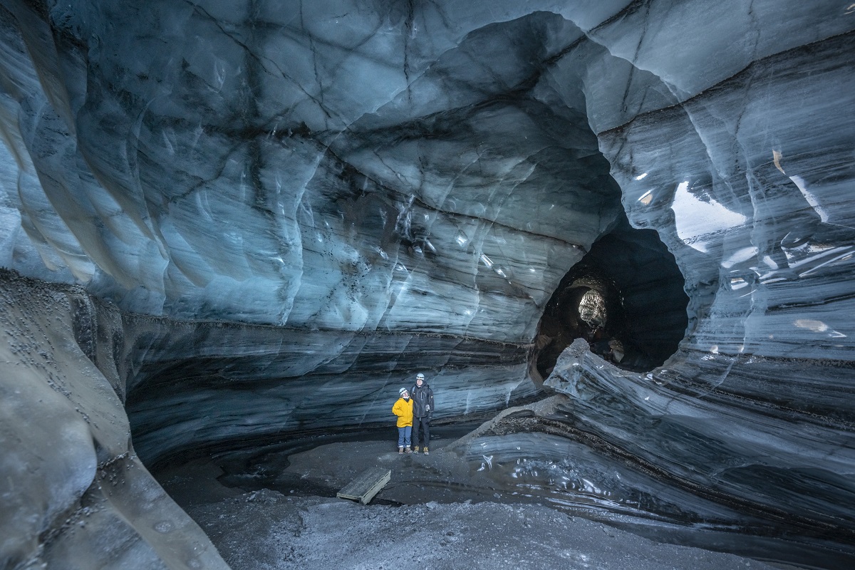 Een stel staat in de blauwe Katla Icecave.