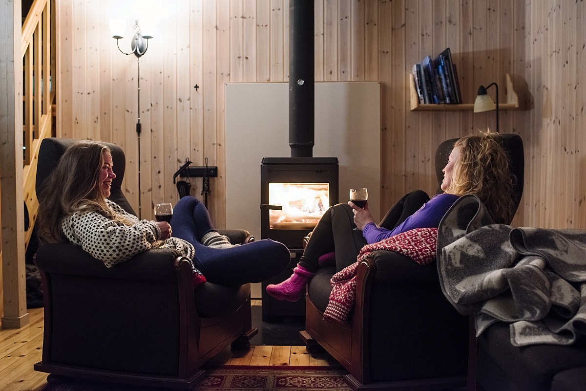 Twee reizigers naast het vuur in de lounge van de Juva hut.