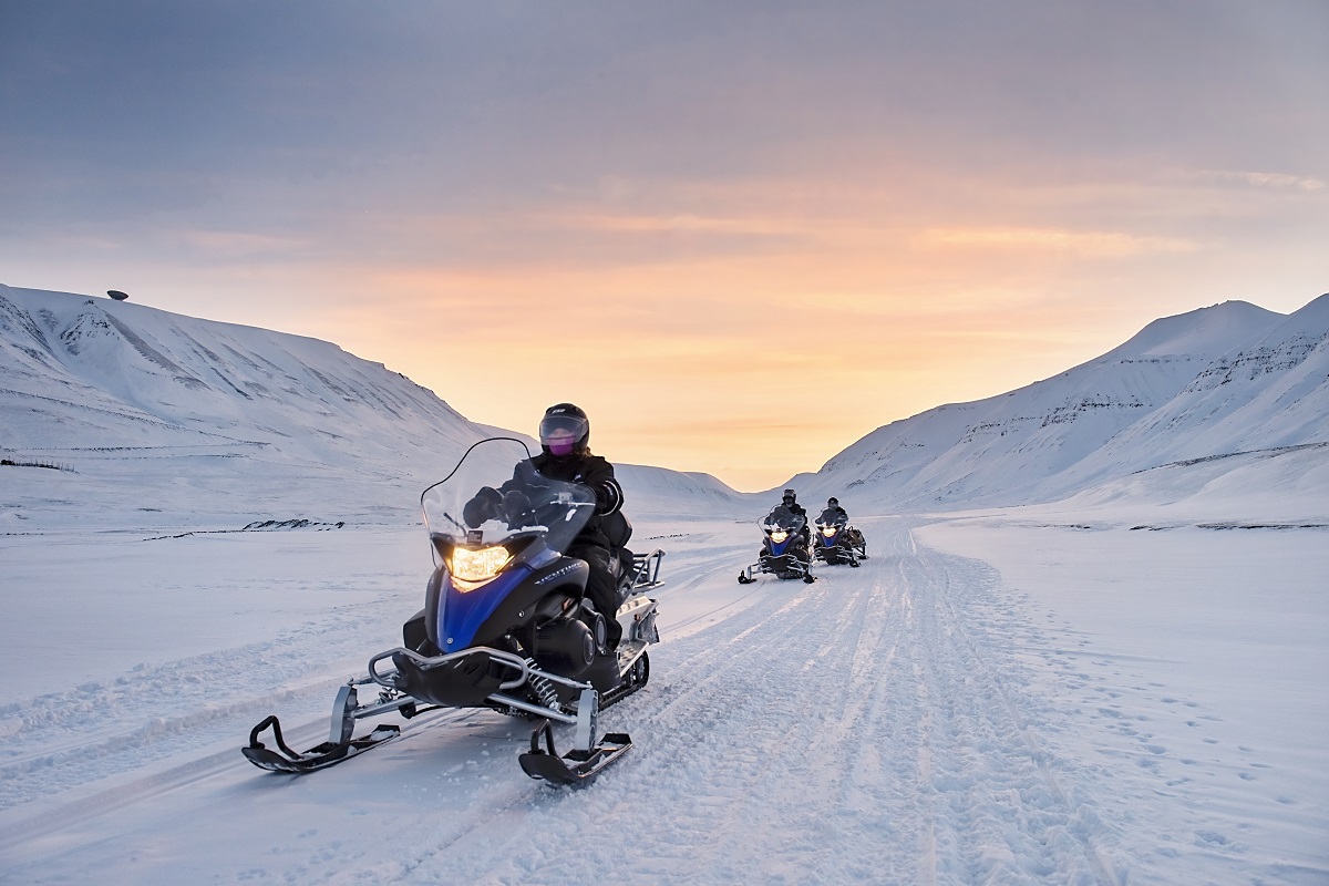 Sneeuwscooters bij zondsopgang in het winterse landschap van Spitsbergen.