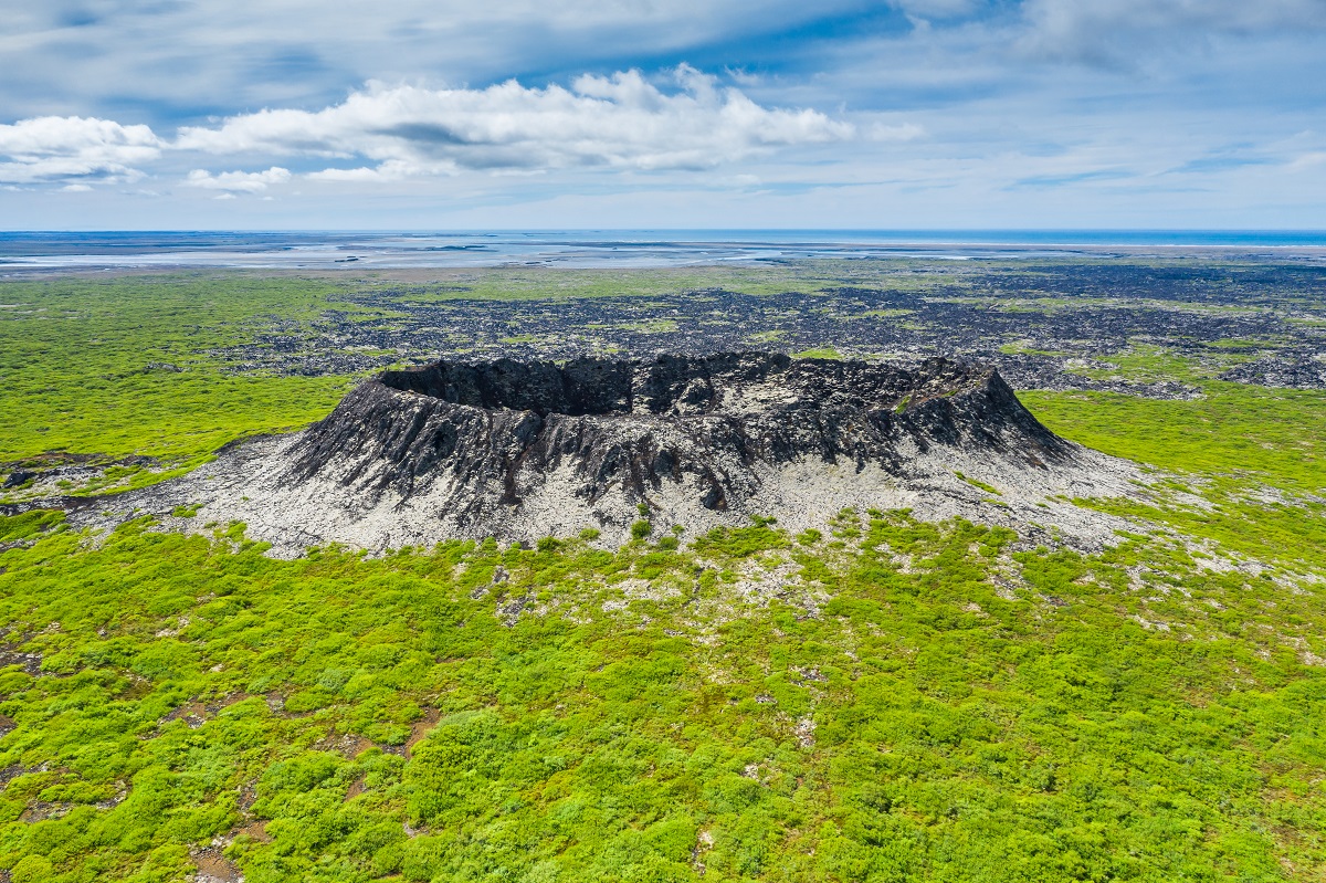 Eldborg krater gelegen in het westen van IJsland rijst op met een lavaveld op de achtergrond.