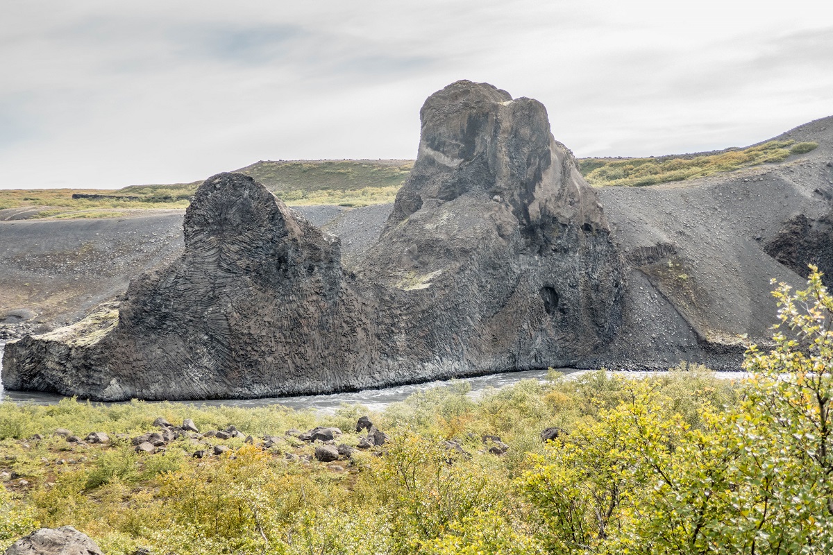 De Hljodaklettar basaltrotsen gelegen in het noorden van IJsland. Voor de rotsen stroomt water langs in het groene landschap.