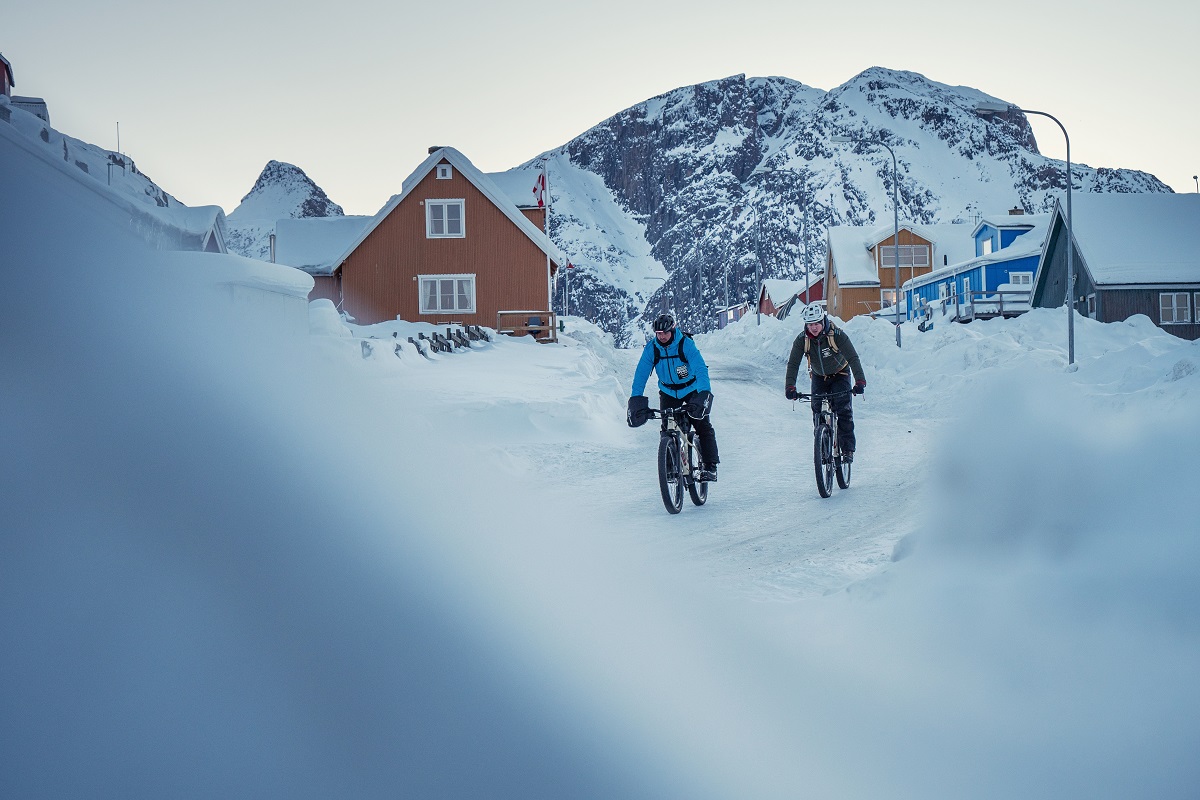 Twee reizigers fietsen door de sneeuw in de winter in Sisimiut gelegen in het westen van Groenland.