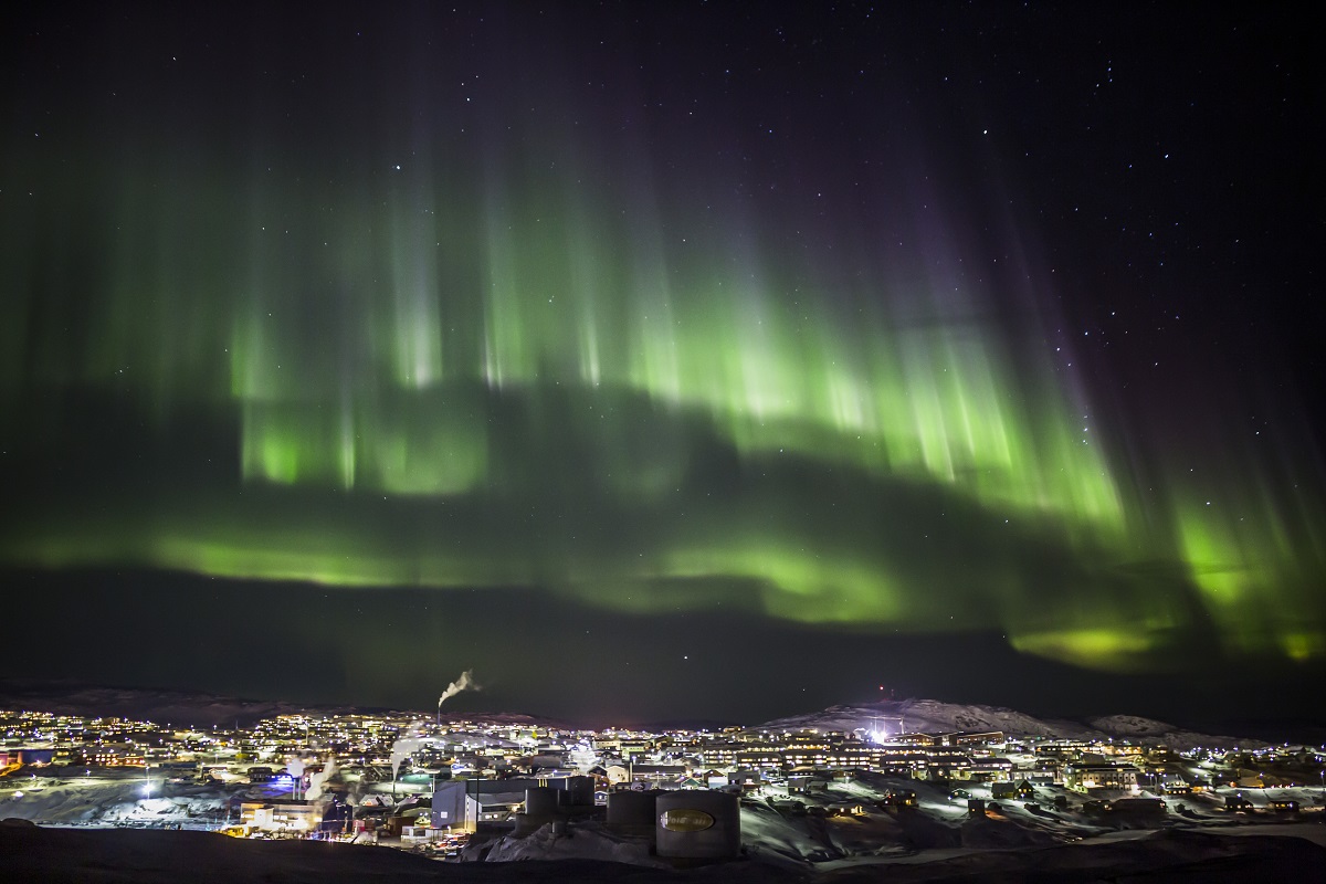 Het noorderlicht schijnt boven de verlichte huizen in Ilulissat in het westen van Groenland.