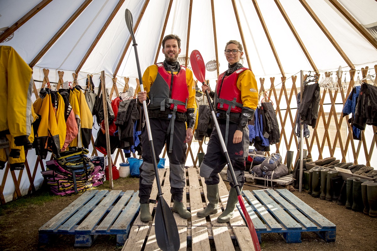 Twee reizigers staan klaar in een tent om te gaan kajakken, met op de achtergrond alle benodigdheden, in het zuiden van Groenland.