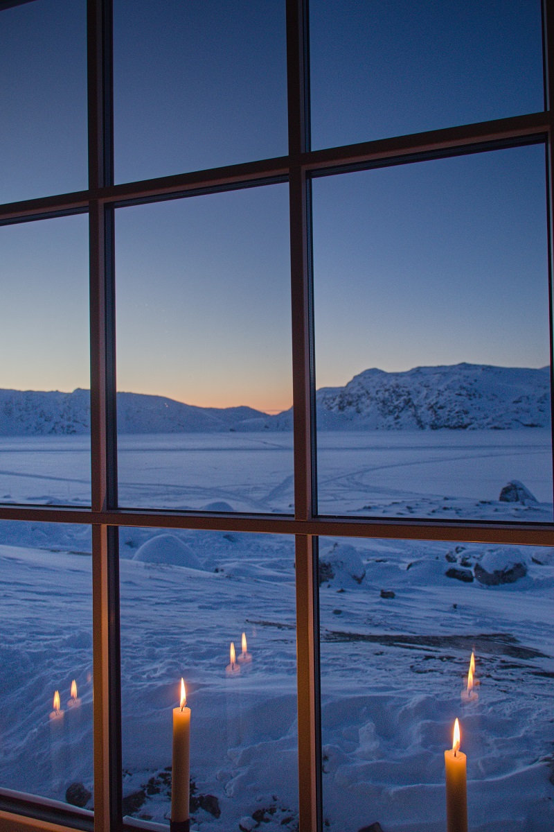 Uitzicht bij kaarslicht op het winterse landschap vanuit de Igloo Lodge, gelegen bij Ilulissat in West-Groenland.