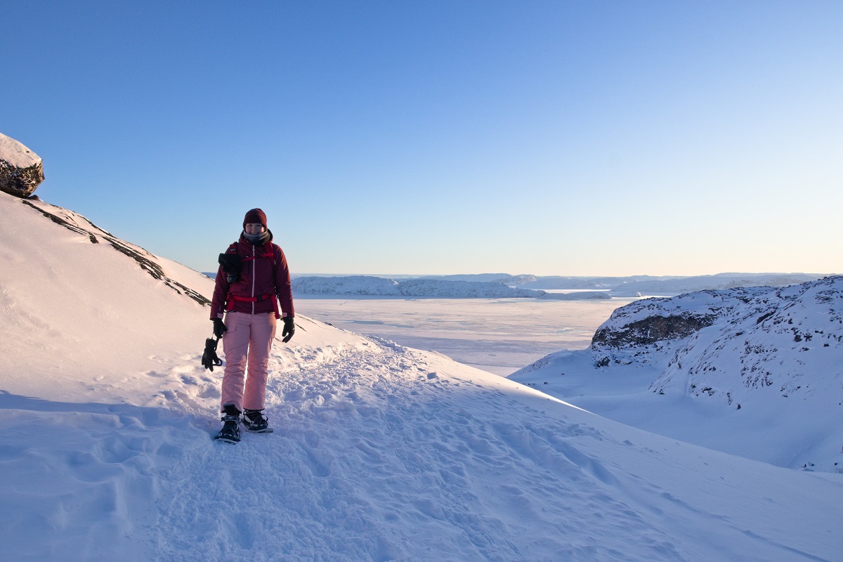 Reiziger maakt een sneeuwschoen wandeling bij het Ilulissat ijsfjord in de winter. Een prachtige landschap waar de zon op schijnt in West-Groenland.