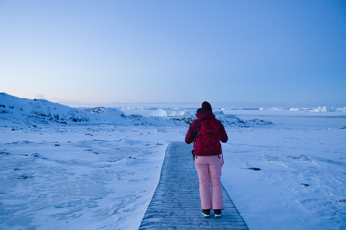 Een wandelaar kijkt uit over het Kangia ijsfjord bedekt met een dikke laag sneeuw in de winter. Gelegen bij Ilulissat in West-Groenland.