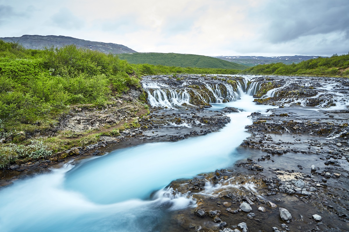 De Bruarfoss waterval met lichtblauw water in een groen landschap. Gelegen in Zuidwest-IJsland.