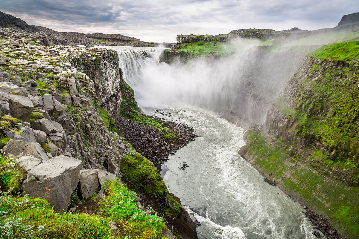 De Dettifoss waterval tussen het groene mos landschap in de zomer.