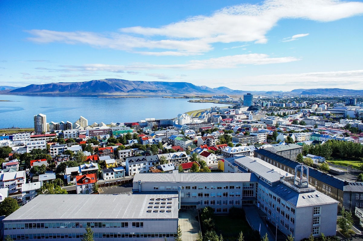 Uitzicht van bovenaf op de kleurrijke huizen van Reykjavik, de hoofdstad van IJsland, met daaromheen de zee en bergen.