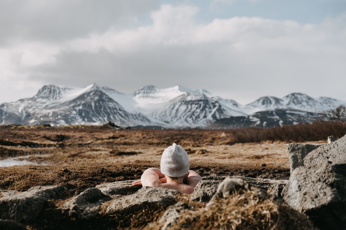 Een reiziger geniet van het uitzicht vanuit de Landbrotalaug natuurlijke warmwaterbron, gelegen op het Snaefellnsnes schiereiland, in West-IJsland.